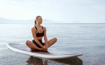 Frau sitzt auf Stand Up Paddle